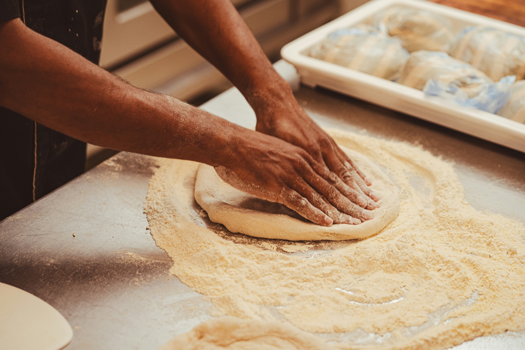 Pizzero estirando la masa a mano sobre harina